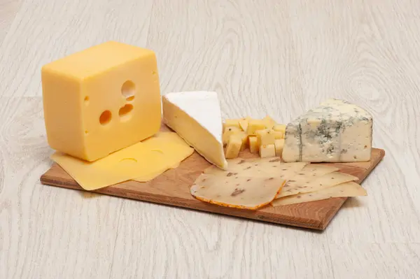 Diversi tipi di formaggio Roquefort, formaggio di noci, brie, su una tavola di legno . — Foto Stock