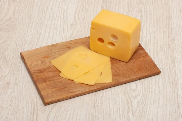 一块奶酪和切片奶酪放在木板上 — 图库照片