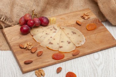 Tahtada dilimlenmiş ceviz peyniri, üzüm, kurutulmuş kayısı ve fındık.