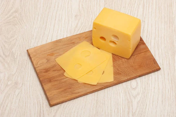 Kawałek sera i ser w plasterkach na drewnianej desce — Zdjęcie stockowe