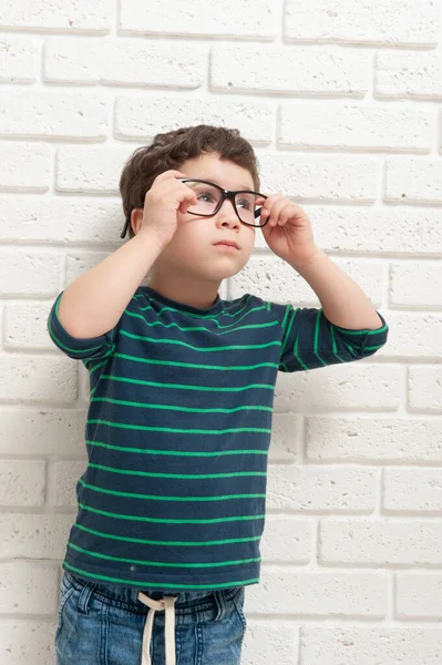 Niño pequeño en gafas contra una pared de ladrillo — Foto de Stock