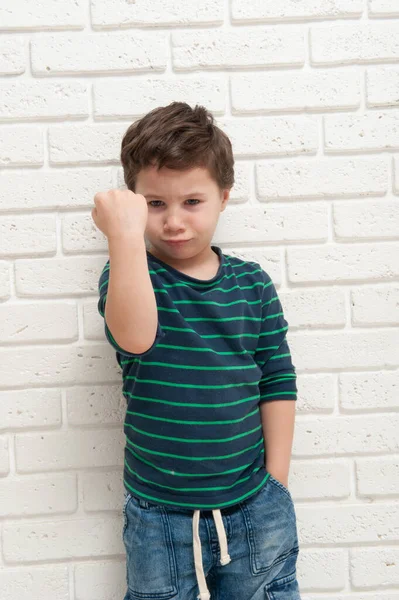 Un niño enojado frunciendo el ceño amenaza con su puño — Foto de Stock