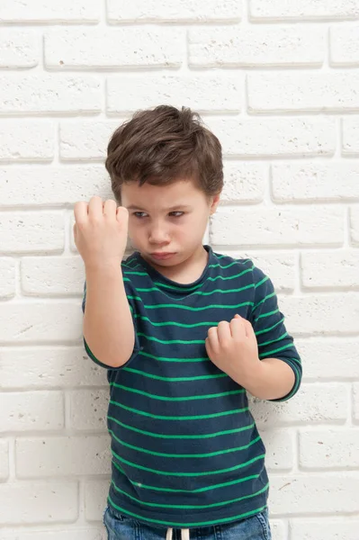 Un niño enojado frunciendo el ceño amenaza con su puño — Foto de Stock