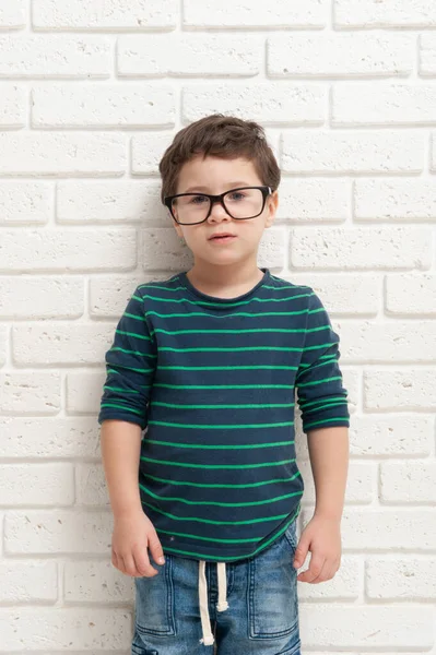 Niño pequeño en gafas contra una pared de ladrillo — Foto de Stock