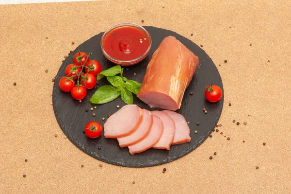 Studené uzené maso s omáčkou, cherry rajčaty a bazalkou na černé grafitové desce — Stock fotografie