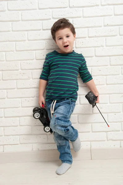 Niño con coche de juguete contra una pared de ladrillo — Foto de Stock