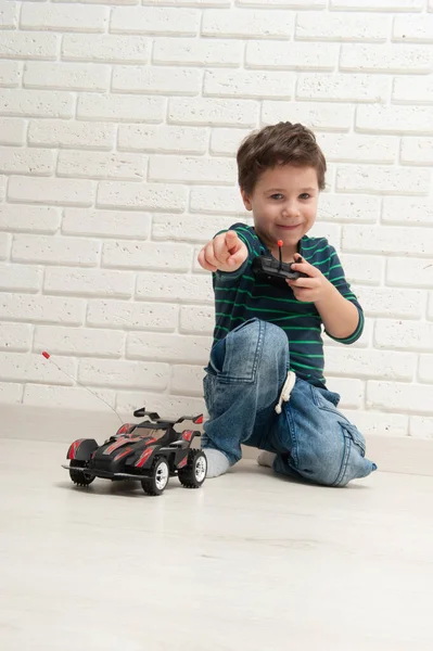 Chłopiec z zabawką samochód na ścianie z cegły — Zdjęcie stockowe