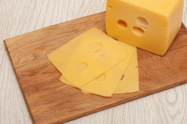 Pedazo de queso y queso en rodajas en una tabla de madera —  Fotos de Stock