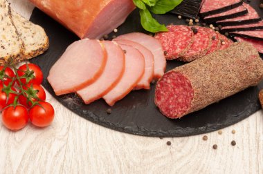 Soslu füme sosis, vişneli domates ve siyah grafit tahtada fesleğen içeren soyut bir arka plan. en üstteki görünüm