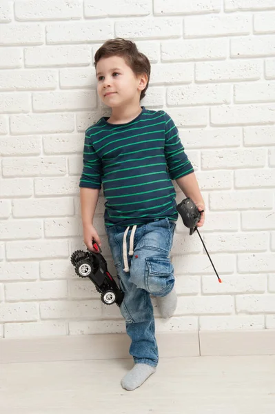 Niño con coche de juguete contra una pared de ladrillo — Foto de Stock