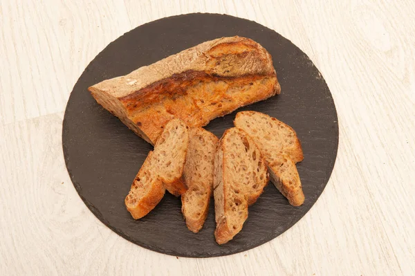 French buckwheat long loaf sliced into pieces on a graphite round board