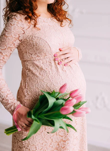 Pancia di una ragazza incinta e tulipani in mano — Foto Stock