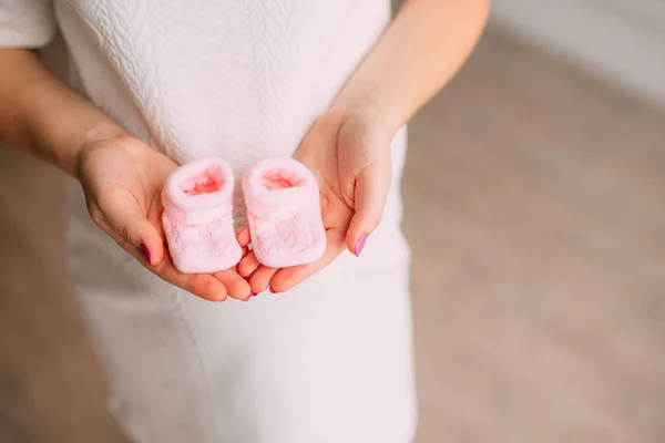 Botinhas de bebê nas mãos de mãe grávida — Fotografia de Stock