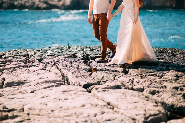 Recién casados en las rocas. Primer plano de las piernas — Foto de Stock