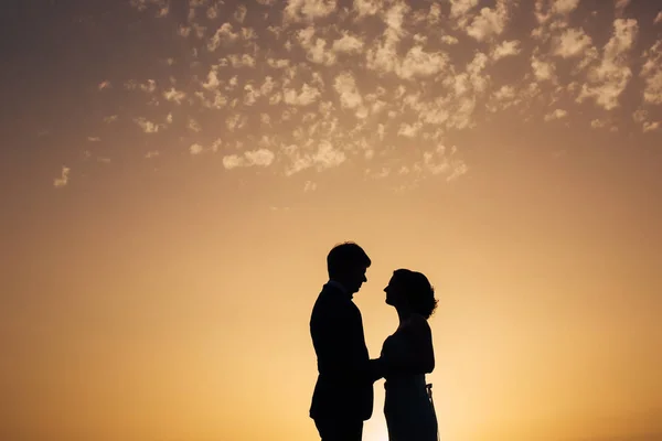 Silhouette of the newlyweds against the sky at sunset. Wedding i — Stock Photo, Image