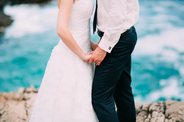 Die Frischvermählten halten sich an den Felsen in der Nähe des Meeres. paar holdi — Stockfoto