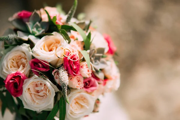 Anillos de boda y ramo de rosas, peonías y suculentas en el — Foto de Stock