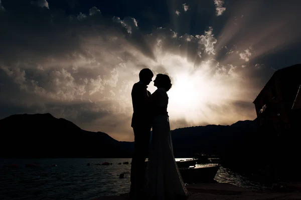 Silhouette d'un couple de jeunes mariés à la mer au coucher du soleil. Mariage en — Photo