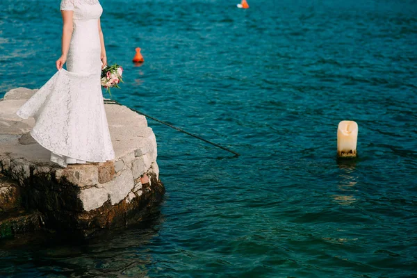 Noiva em um vestido branco com um buquê em mãos em uma torta de concreto — Fotografia de Stock