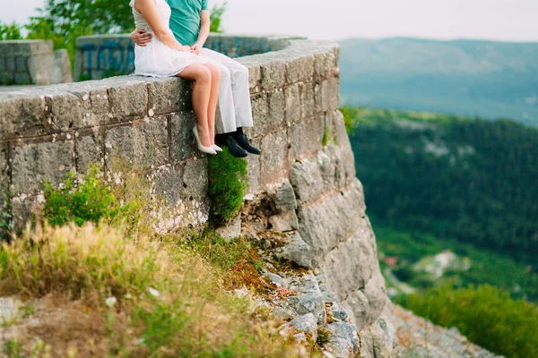 Die Frischvermählten sitzen am Abgrund. Beine aus nächster Nähe. hochzeit — Stockfoto