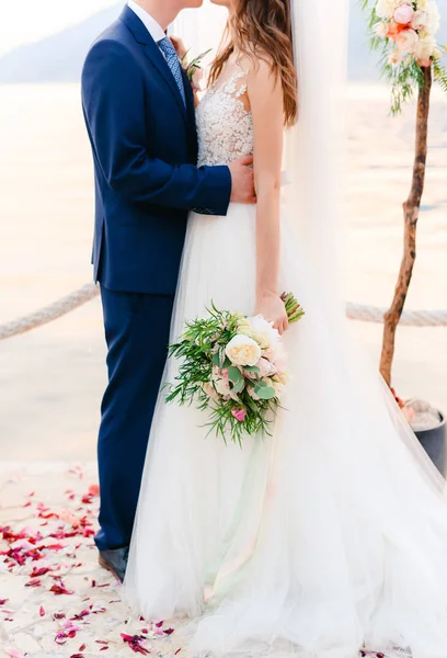 De bruidegom omarmt de bruid op het strand. Bruiloft in Montenegro — Stockfoto