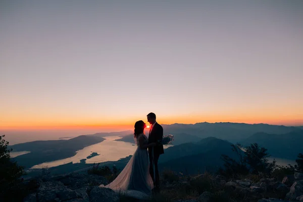 Silhueta de um casal recém-casado nas montanhas ao pôr-do-sol. Casamento — Fotografia de Stock