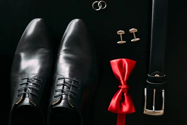 Black mans shoes, cufflinks, wedding rings, a black belt and a — Stock Photo, Image