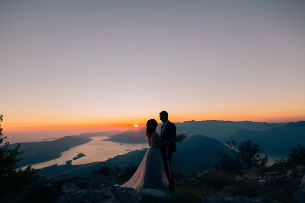 Bir yeni evli çift gün batımında dağlarda silüeti. Düğünü