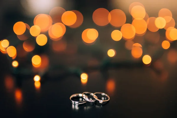 Wedding rings on a yellow background bokeh of garlands. Magical — Stock Photo, Image