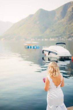 Bir yat deniz kıyısında bir kız bakar.