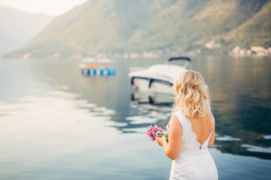 Bir yat deniz kıyısında bir kız bakar.