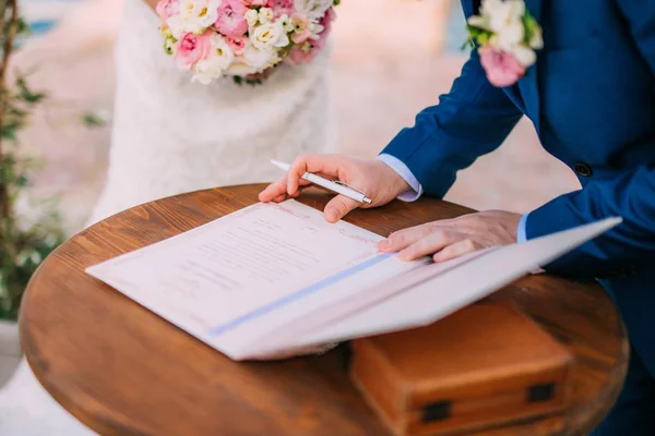 Новобрачные ставят подписи в акте регистрации брака — стоковое фото