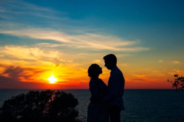 Batan güneşin arka planda bir yeni evli çift silüeti