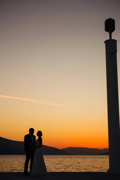 Silueta de una pareja recién casada en el fondo del sol poniente — Foto de Stock