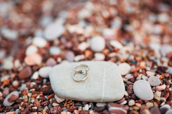 Trauringe von Frischvermählten auf Kieselsteinen am Strand — Stockfoto
