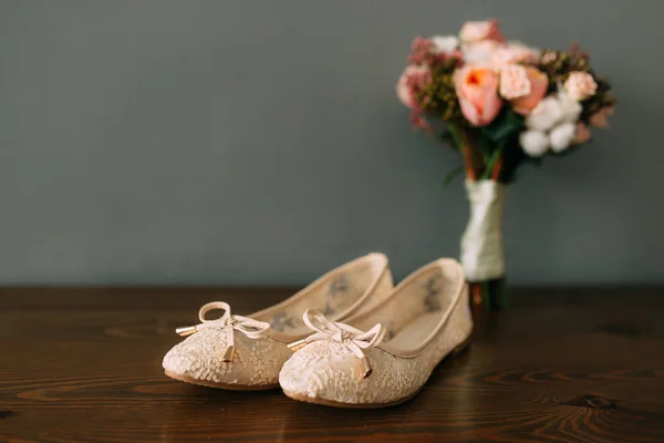 Кремовая обувь невесты на зеленом столе на деревянном столе — стоковое фото