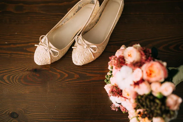 Los zapatos de crema de la novia sobre verde sobre la mesa de madera —  Fotos de Stock