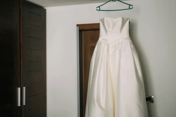 The brides dress on a hanger in the room