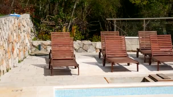 Houten ligstoelen, donker hout in lege zwembad — Stockvideo