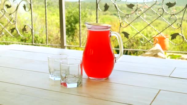Compota de fruta roja en un decantador y dos vasos — Vídeo de stock