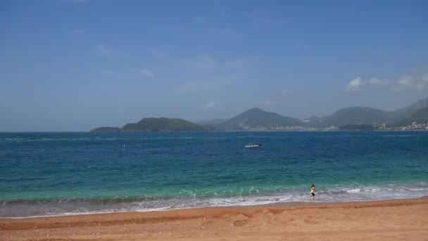 Une petite fille court le long de la plage. Un enfant joue dessus — Video