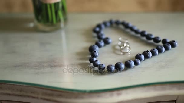 Anillos de boda en un corazón de un arándano en una mesa, al lado de un br — Vídeo de stock