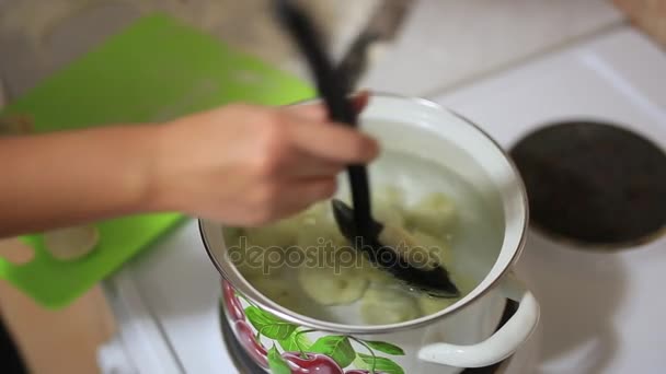 Девочка готовит пельмени на сковороде. Девушка готовит еду. — стоковое видео