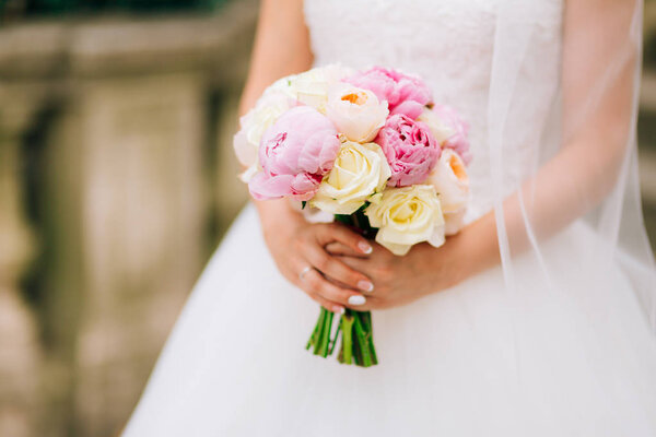 Wedding roses and peonies in the hands of the bride. Wedding in