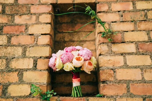 Bouquet of peonies on the background of the stone wall of red br