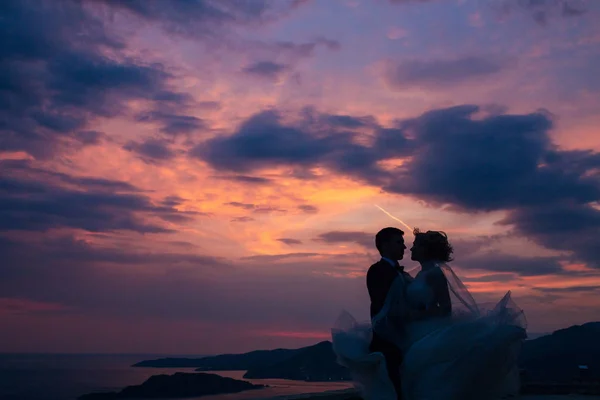 Silhueta dos recém-casados contra o céu ao pôr-do-sol. Casamento i — Fotografia de Stock