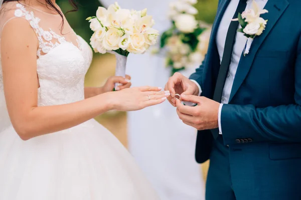 The groom dresses a ring on the finger of the bride at a wedding