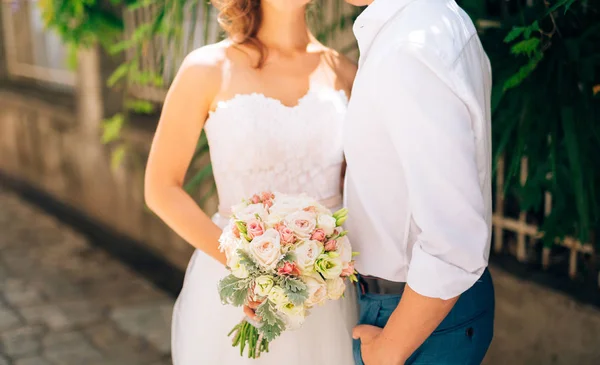 Brudgummen omfamnar bruden i gamla stan. Bröllop i Montene — Stockfoto