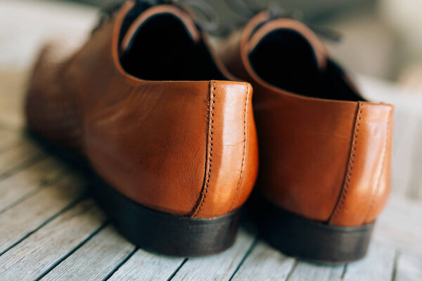 Brown man shoes with laces on wooden background