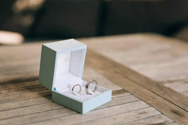 Anéis de casamento em uma textura de madeira leve em uma caixa azul. Casamento j — Fotografia de Stock